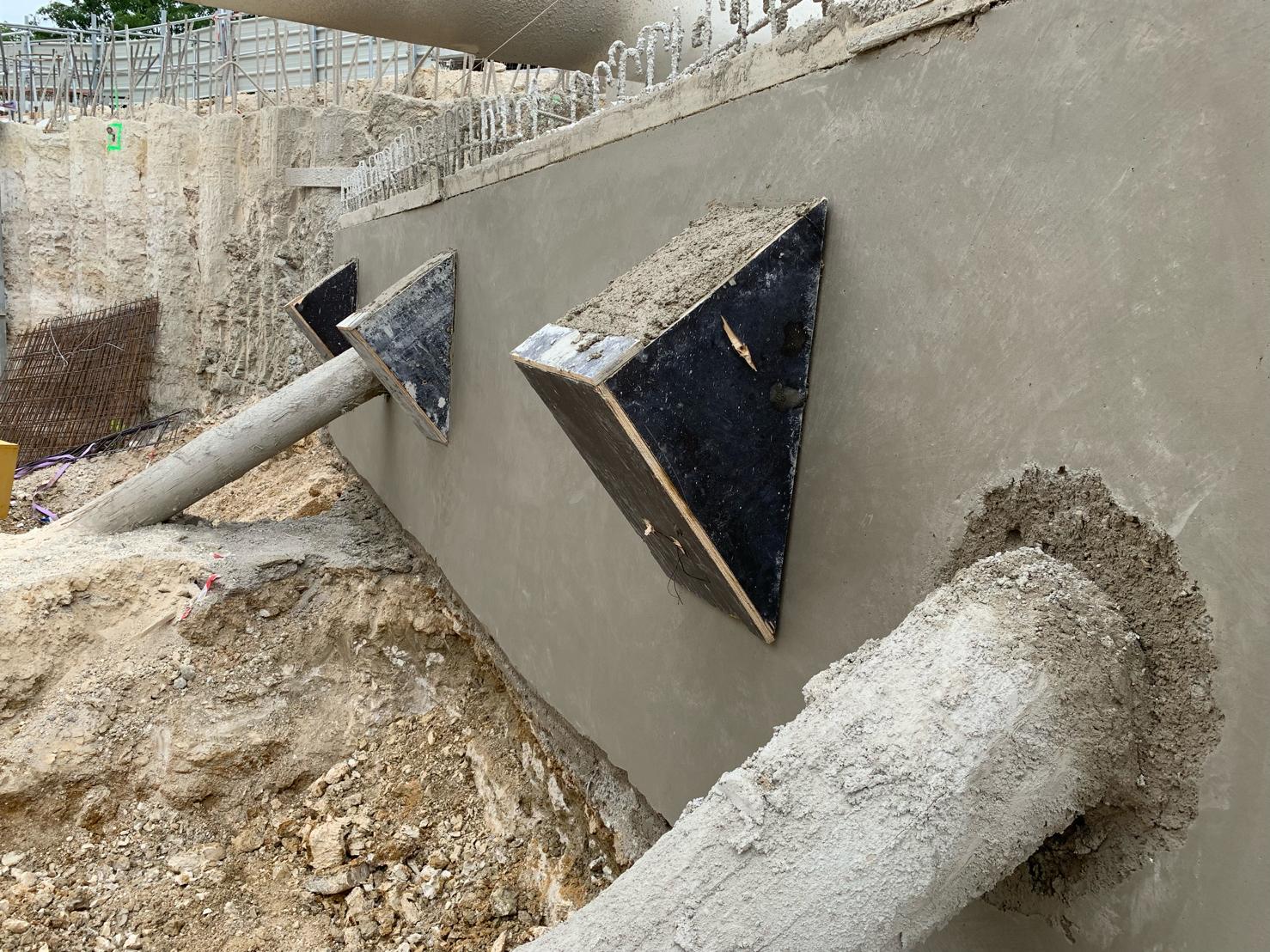 Lance de projection posée contre un voile en béton fraîchement projeté