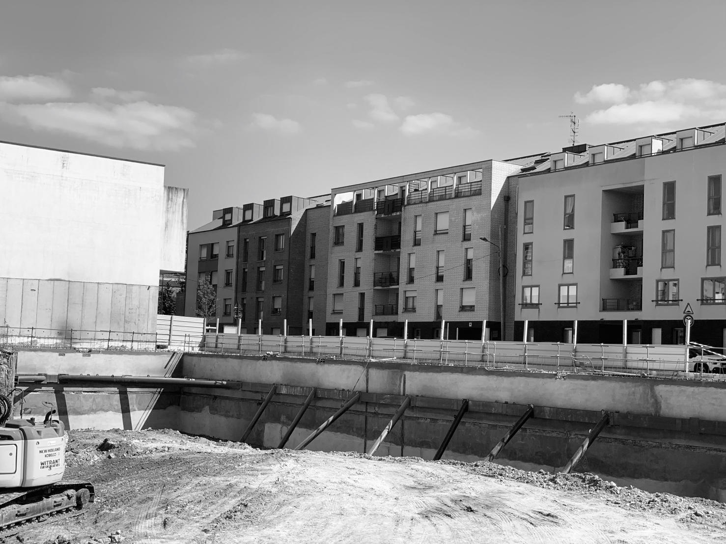 Vue en noir et blanc d'un immeuble en construction au-dessus d'une fouille soutenue